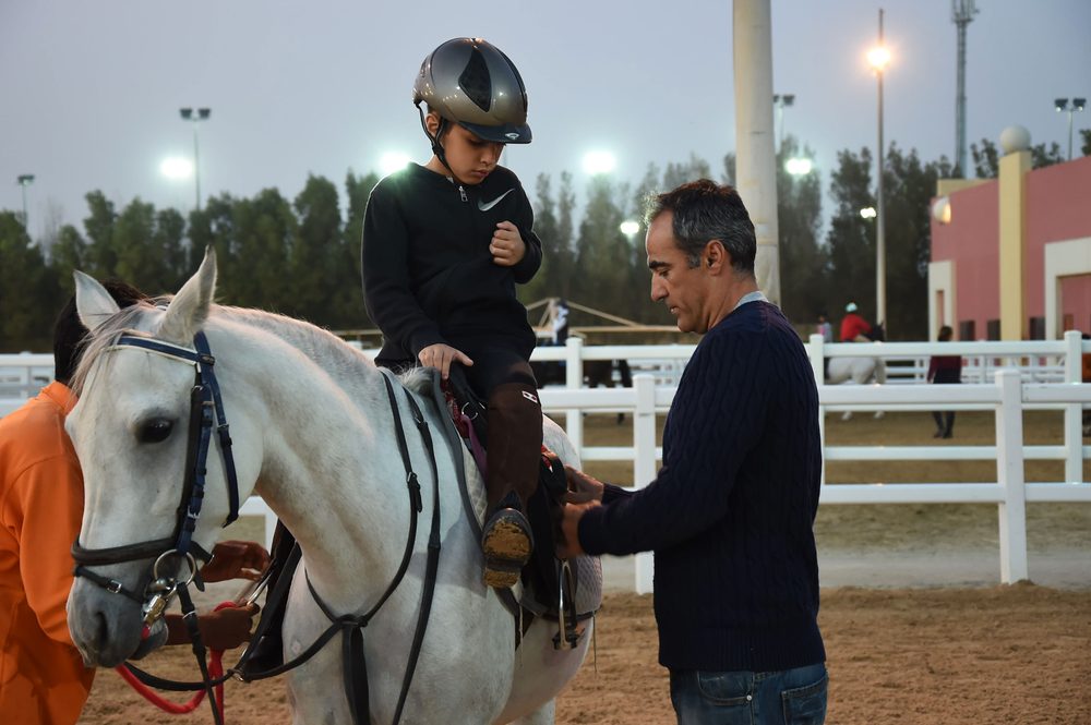 Instructor guiding a young rider during a lesson